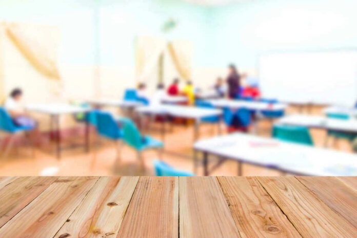 Blurred classroom with students and a wooden foreground.