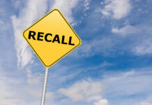 Yellow sign with RECALL text against blue sky.