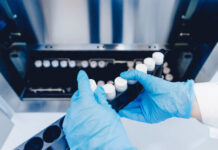 Person in blue gloves handling test tubes in a laboratory