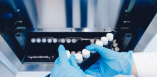 Person in blue gloves handling test tubes in a laboratory