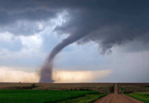 Tornado touching down in an open field area.
