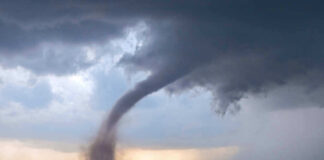 Tornado touching down in an open field area.