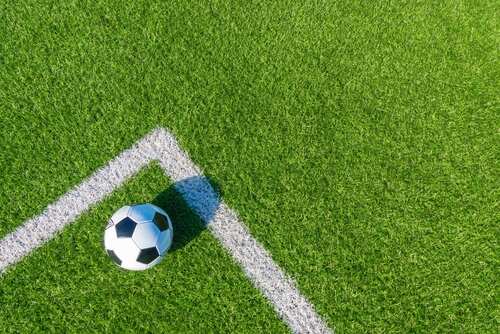 shutterstock_2042462933 (1).jpg A soccer ball resting on a green artificial turf field near the corner