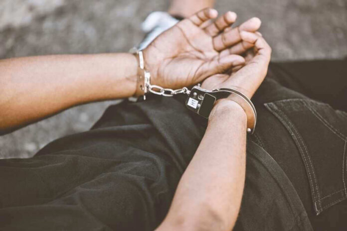 shutterstock_2224946127.jpg Person in handcuffs with hands behind back.