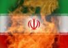 Pentagon’s Iran Strikes – Why Now? Iranian flag with flames in the background