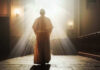 SHOCK Apology: Church’s Slavery Role Exposed Person in religious attire bathed in sunlight.