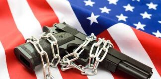 A handgun wrapped in chains on an American flag