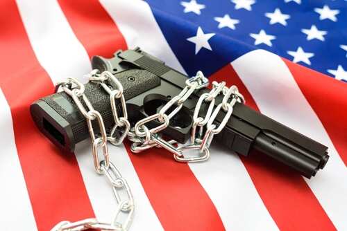 shutterstock_2317509647.jpg A handgun wrapped in chains on an American flag