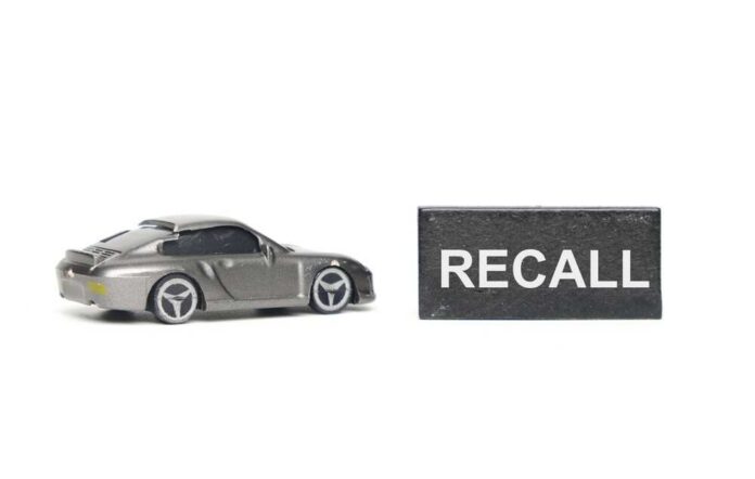 A,Picture,Of,Car,Diorama,Miniature,With,Recall,Word,At A miniature gray sports car next to a black sign that reads 'RECALL'