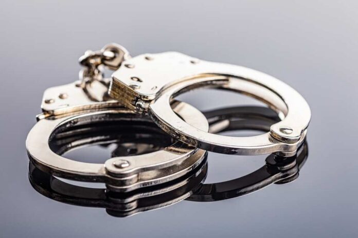 Close-up of metallic handcuffs on a reflective surface