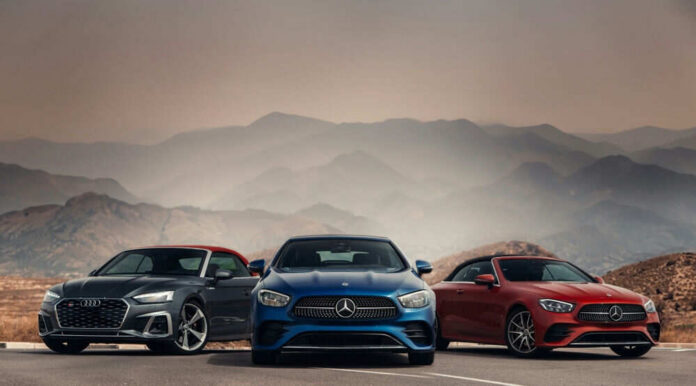 shutterstock_2442509933 Three luxury cars in front of mountain landscape