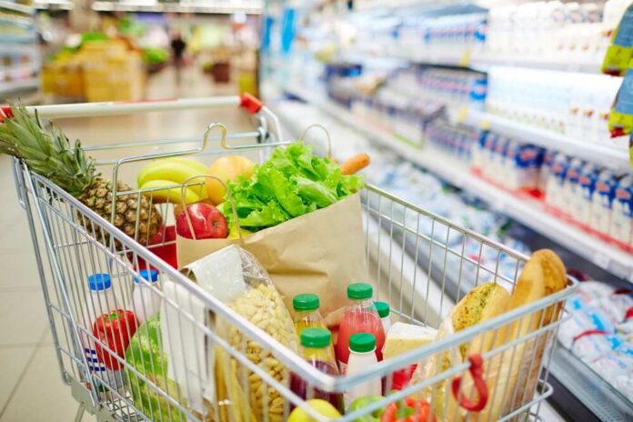 A shopping cart filled with fresh fruits, vegetables, and groceries