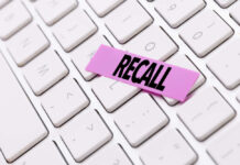 Silent Threat: Recall Shakes Trust A pink sticky note with the word 'RECALL' placed on a white keyboard