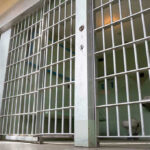 Cruise Cabin Horror: Judge Slams Cell Door Empty prison cell with metal bars and toilet.