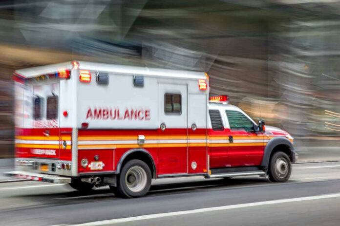 shutterstock_1495131698 Red and white ambulance driving on a city street.