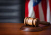 VIDEO: Plea Deal Buries Serial Killer’s Secrets? A wooden gavel resting on a sound block with an American flag in the background