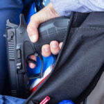 VIDEO: Classroom Shooting – 3 Dead A hand holding a gun inside a backpack