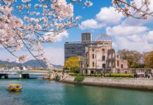 Vanished In Kyoto — Then Found Dead View of the Hiroshima Peace Memorial with cherry blossoms in the foreground