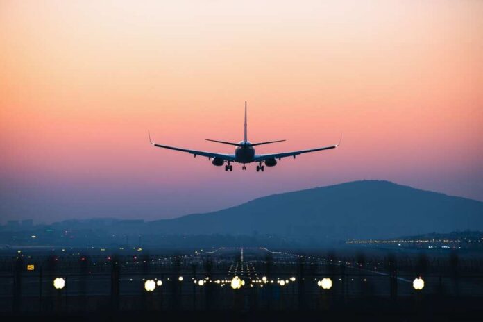 An,Airplane,Departing,From,Airport,During,Sunset An airplane approaching for landing against a colorful sunset sky