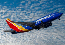 Southwest Backtracks Angering Many Customers Southwest airplane on the air with blu sky and white clouds.