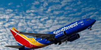 Southwest airplane on the air with blu sky and white clouds.