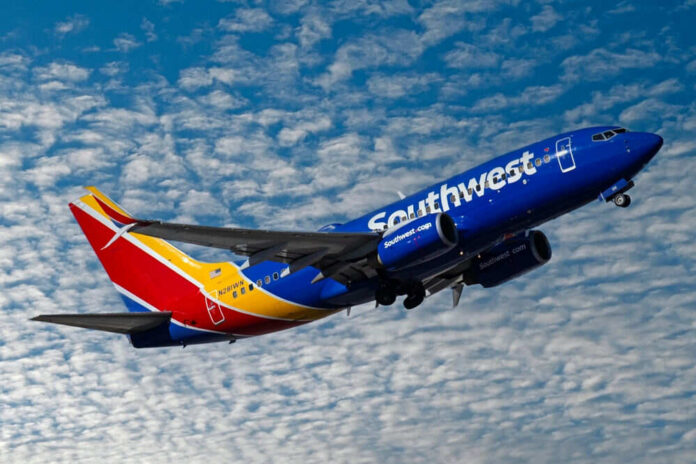 Southwest airplane on the air with blu sky and white clouds.