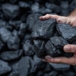Trump Drops $700M Coal Bombshell on Enviros Hands holding several pieces of black coal against a background of more coal