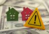 Mortgage Shocker: THIS Status Now Counts?! Colorful house models and a warning sign on dollar bills