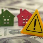 Mortgage Shocker: THIS Status Now Counts?! Colorful house models and a warning sign on dollar bills