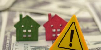 Colorful house models and a warning sign on dollar bills