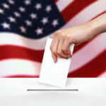 Georgia Showdown Underway — Senate Control at Stake Hand dropping ballot into box, American flag background.