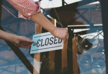 Pizza Chain Freefall: 50 Shops Vanish Person flipping closed sign on glass door