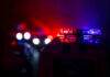 Violent Chaos: Six Down, Shooter Vanishes Police car lights shining in the dark.