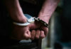 Close-up of hands in handcuffs behind back.