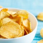 A bowl filled with golden, crispy potato chips on a countertop