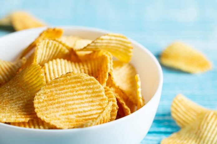 Close-up,,A,Plate,Of,Potato,Chips,On,A,Blurred,Background. A bowl filled with golden, crispy potato chips on a countertop