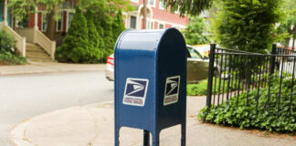 Blue USPS mailbox on a residential street corner.