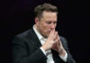 Bezos vs. Musk: Space Phone Showdown Elon Musk in a suit deep in thought, black background.