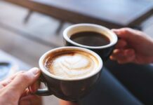 Two hands holding cups of coffee, latte and black coffee