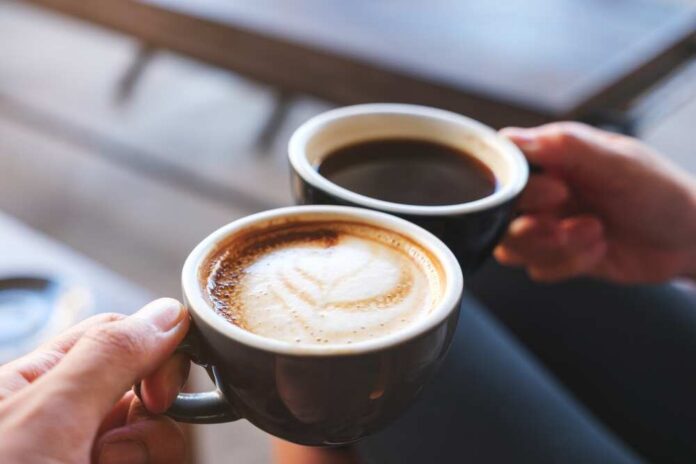 Closeup,Image,Of,A,Man,And,A,Woman,Clinking,Coffee Two hands holding cups of coffee, latte and black coffee
