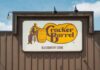 Biscuit Bloodbath at Cracker Barrel Sign for Cracker Barrel Old Country Store featuring a man sitting on a barrel