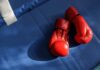 An empty boxing ring illuminated by bright lights in a sports arena