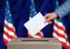 Hand casting a vote into a ballot box.