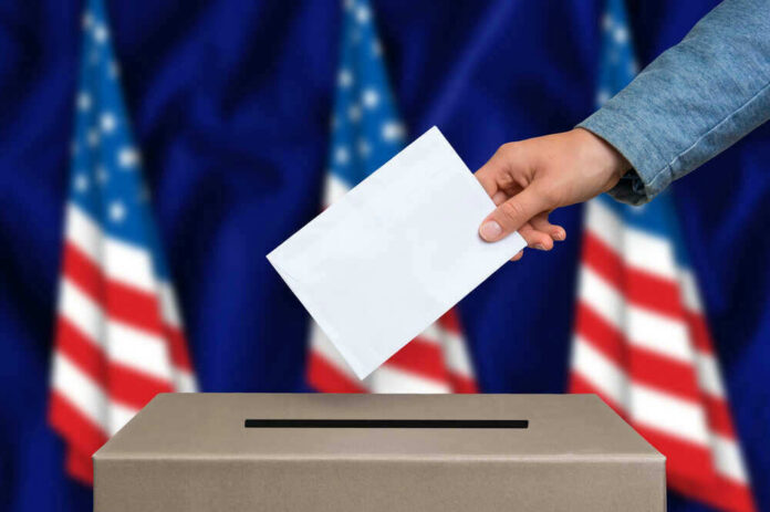 shutterstock_495494674 Hand casting a vote into a ballot box.