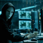 Rolling Spies? America Slams Door Shut Person in hoodie and mask using computer, multiple screens.