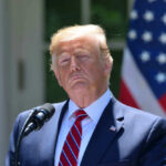 Bank Purge Hits Trump Empire Donald Trump speaking with US flag in the back.