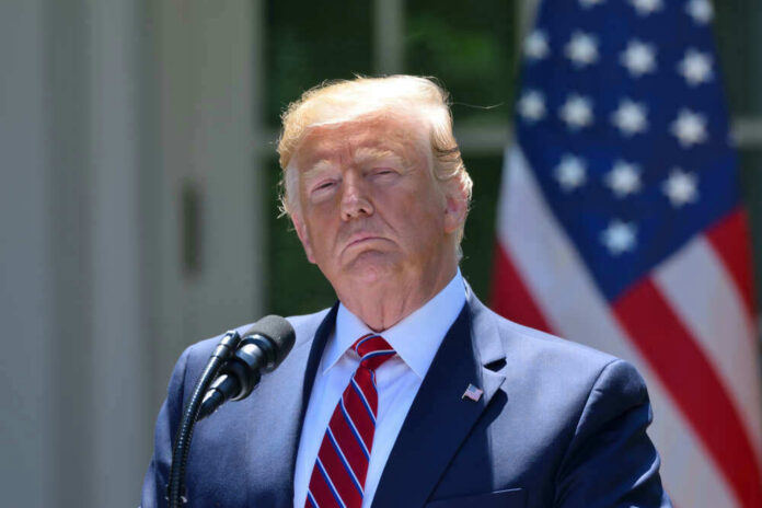 shutterstock_1432764869 Donald Trump speaking with US flag in the back.