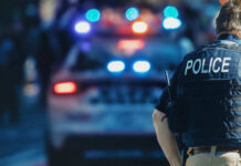 Nightmare: Home Erupts, Bodies Found (VIDEO) Police officer stands near patrol car with lights flashing.