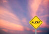 Mystery Outbreak Claims Two Yellow alert sign against a colorful sunset sky