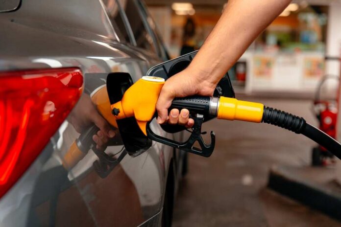 Hand,Man,Refill,And,Filling,Oil,Gas,Fuel,At,Station. A person refueling a car at a gas station